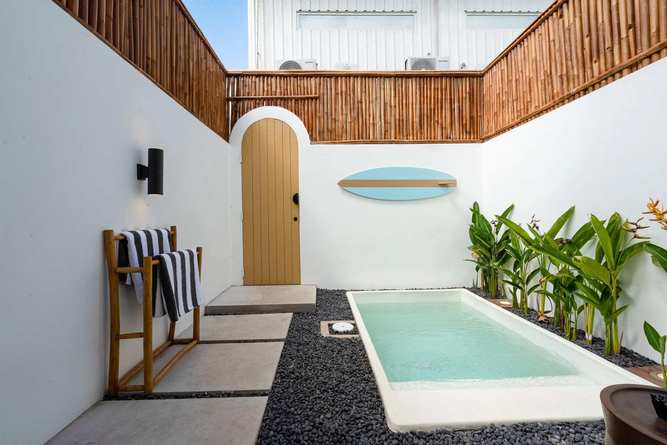 Wide view of the Villa Mares pool courtyard with surfboard wall decor and tropical planting