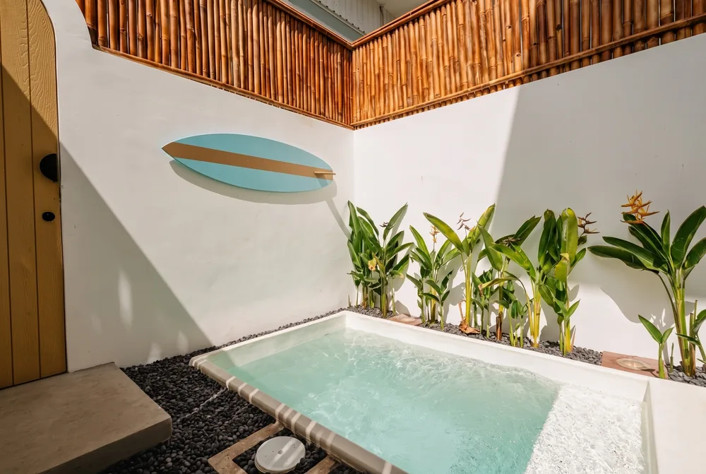 Finished Villa Mares pool courtyard with a blue surfboard wall feature and tropical planting beside the plunge pool